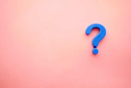 A blue question mark symbol resting on a pink background