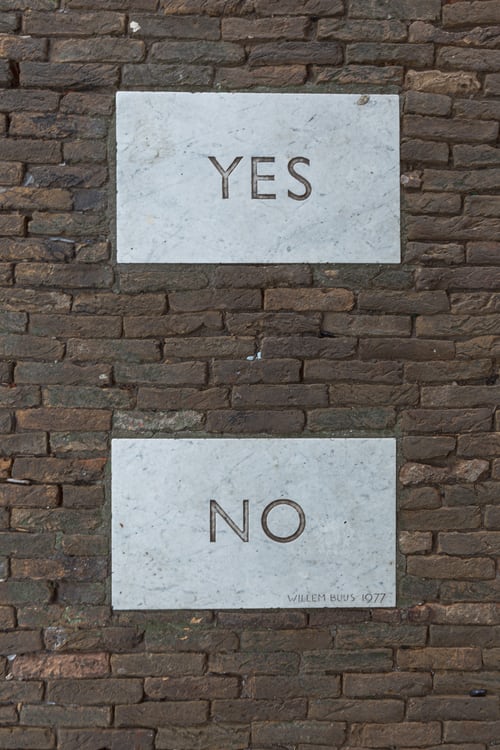Yes and no plaques on a brick wall symbolising key decisions to prospective decision-makers
