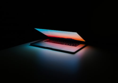 A closing MacBook Pro in a dark room