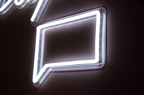 A white fluorescent chatbox sign on a wall