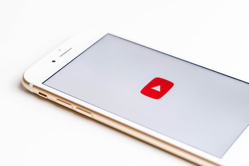 An iPhone with the YouTube logo resting on a white background