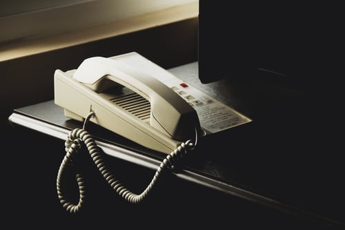 A white office phone resting on a table in a dark office