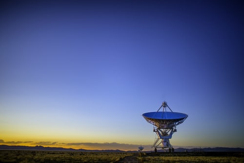 A large telephone satellite against the backdrop of a clear sky sunset