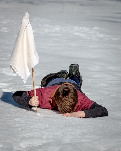 A man lying in the snow having surrendered due to a series of failed cold calls