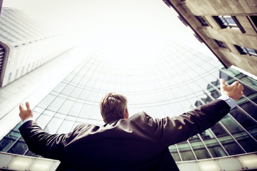 An insurance salesman holding his arms outstretched and looking to the sky