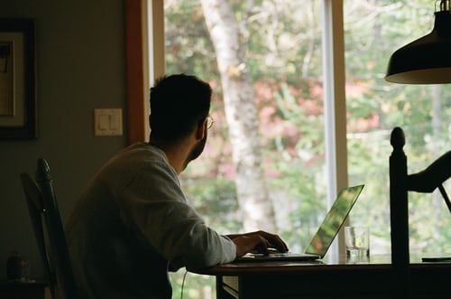 A man working remotely staring out of the window