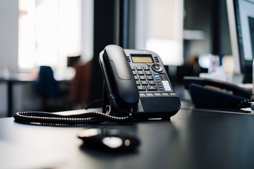 A black office telephone sitting on a black office desk in a sales office