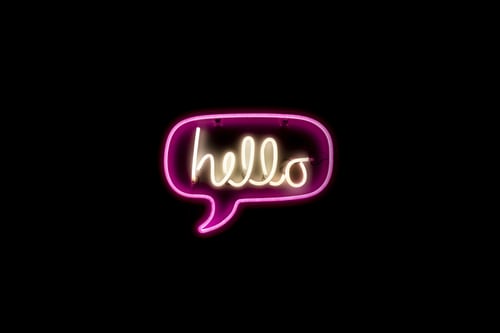 A fluorescent hello speech bubble against a black background