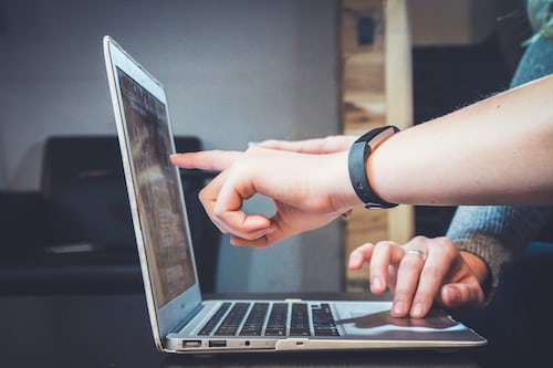 Two workers engaging a customer through screen-sharing on a laptop