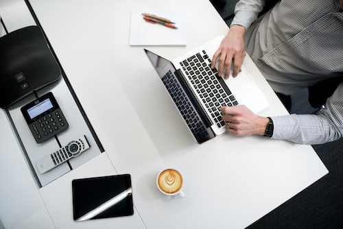 A salesman at his laptop with a fresh coffee