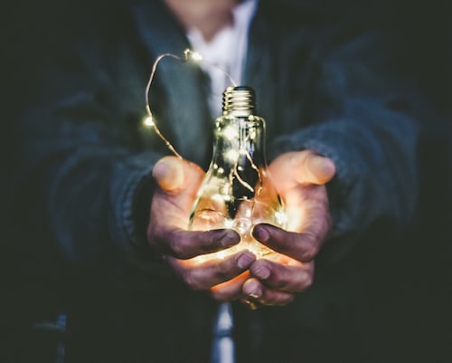 A person holding a lit lightbulb to signify a new idea