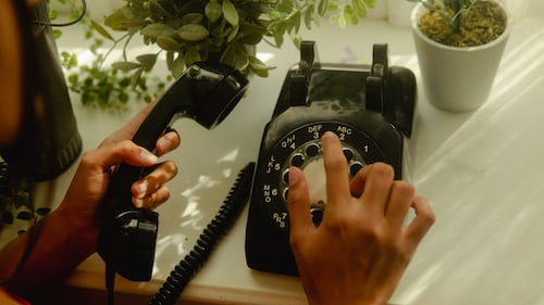 A sales person using a traditional bblack phone to contact a lead