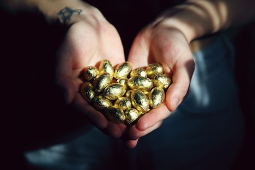 A person holding a handful of golden eggs as a sales incentive