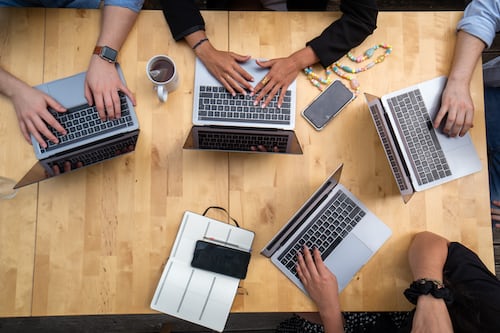 Four people working together in a meeting room to discuss digital agency software solutions