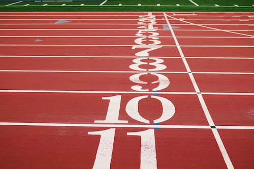 The starting line of an athletes race track with numbers printed in each lane