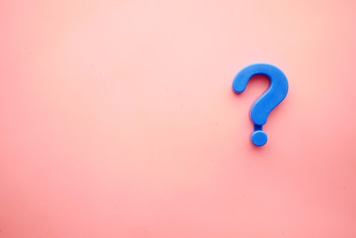 A blue question mark magnet on a pink background