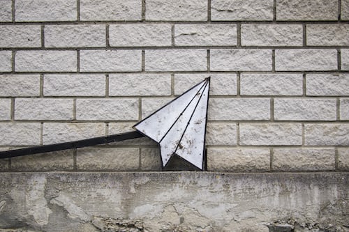 A white paper airplane email icon resting on the floor