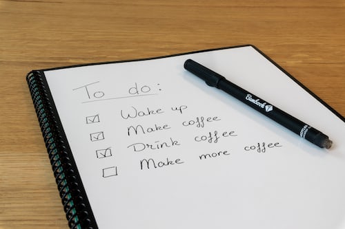 A to do list on a white pad with a pen and paper
