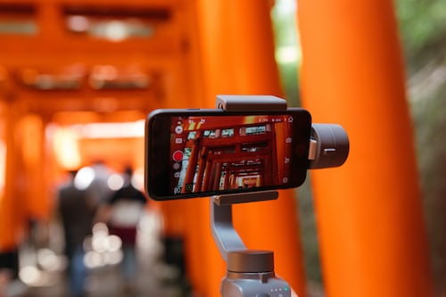 An iPhone resting on a gimbal for filming in an orange room