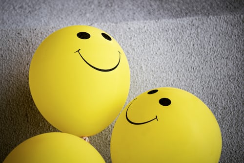Three yellow smiley face balloons resting on the floor