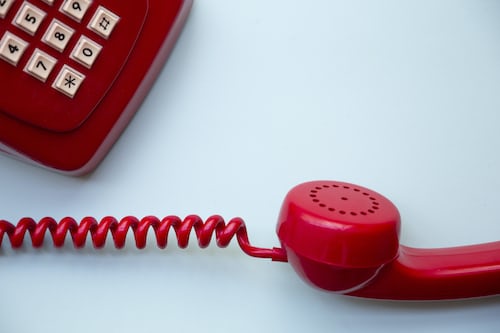 A red corded telephone for telesales agents