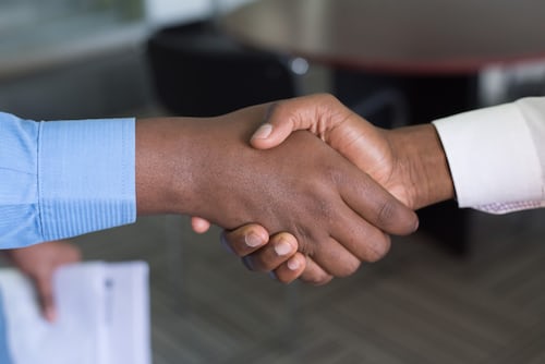 Two people of different ethnicities shaking hands after a business meeting