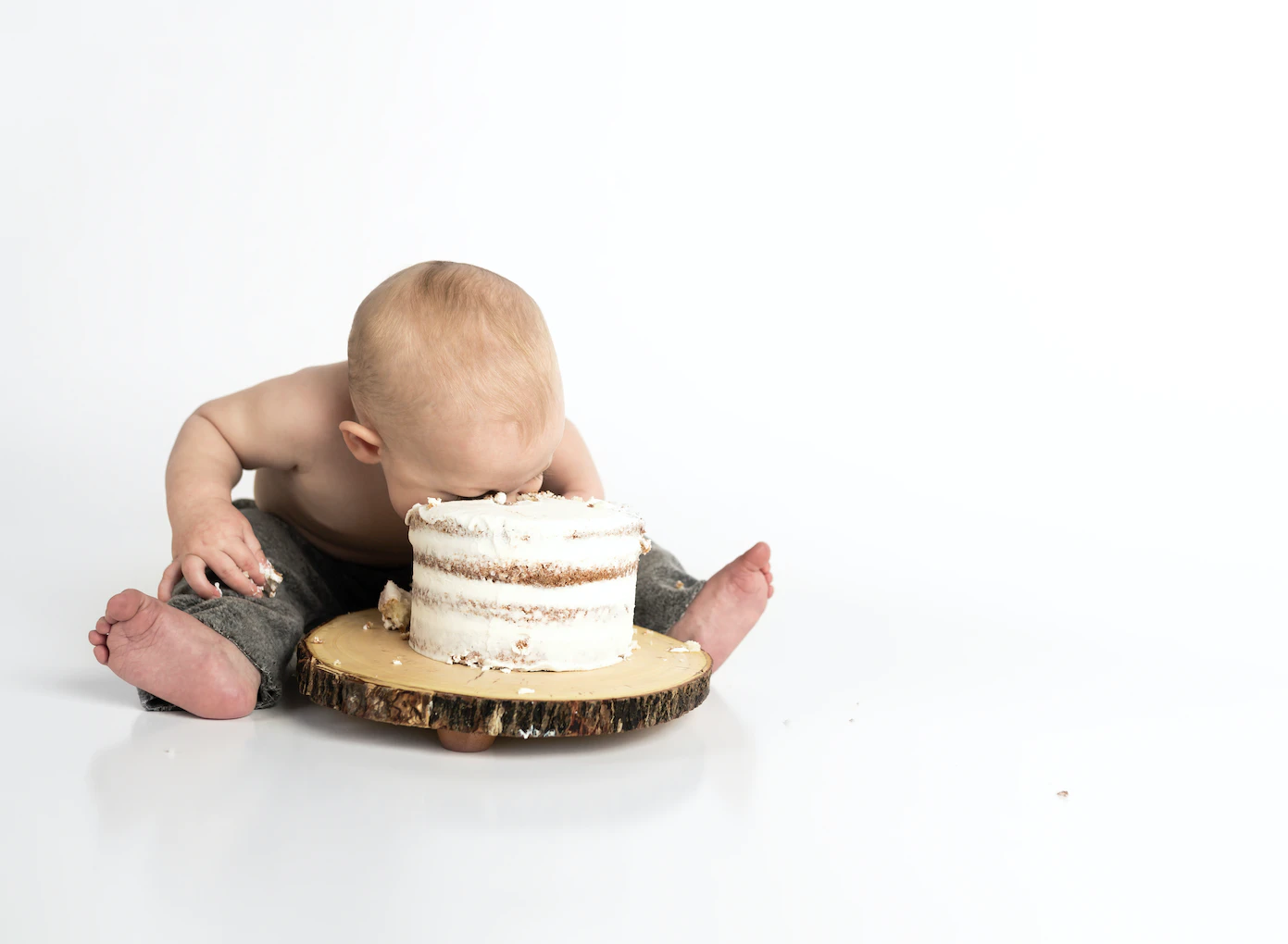 A baby eating a whole cake against a white background